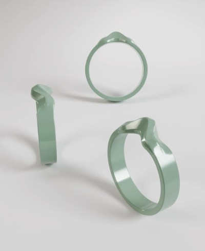 3D render of a pastel green wide band ring with a fluid, wavy, or sculptural design at the top, shown from multiple angles including top and side views.